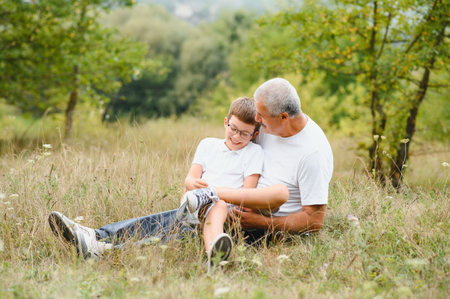 Happy grandfather embracing grandson in park.の写真素材