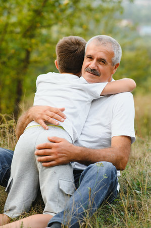 Happy grandfather embracing grandson in park.の写真素材
