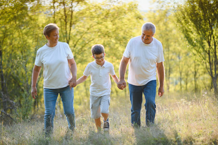 Grandparents walking with them grandson in summer sunset.