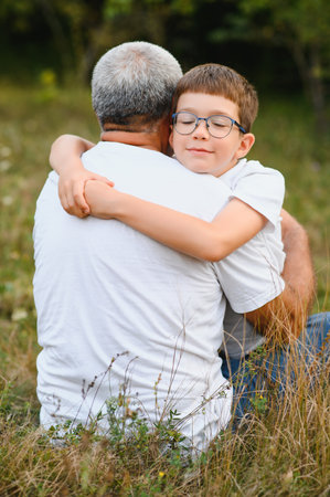 Happy grandfather embracing grandson in park.の写真素材