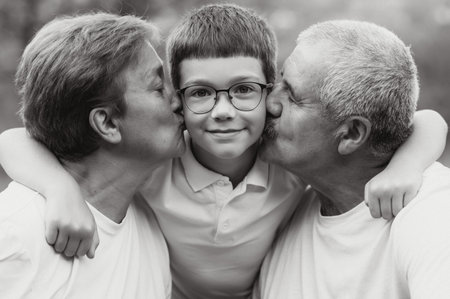 Grandparents with their grandson. They are playing on meadow and enjoying the sunset.の写真素材