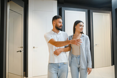 Portrait of smiling young man and woman shopping in the hardware store choosing different door options.の写真素材