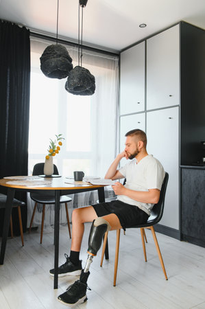 Portrait of man with prosthetic leg reading book while relaxing at home, copy space.