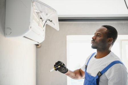 Happy Young African Male Technician Repairing Air Conditioner.の写真素材