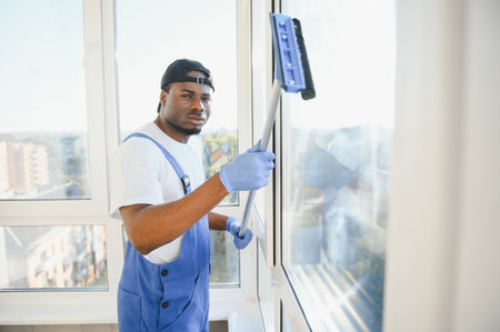 Young man cleaning window in office.