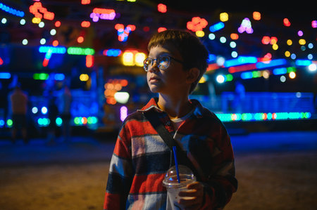 A cute Caucasian boy, a child, came to the amusement park to have fun, play and ride a merry-go-round. A child standing in front of a merry-go-roundの写真素材