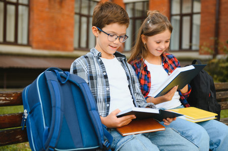 Children read books sitting on bench in school yard. Back to school. Beginning of school lessons.の写真素材