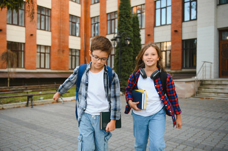 Happy schoolchildren near the school. A boy and a girl are primary school students. School friendship.の写真素材