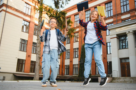 Happy school kids friends boy and girl with backpacks walking and laughing having fun together near school building outside outdoor after lessons.の写真素材