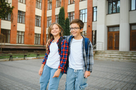 Happy schoolchildren near the school. A boy and a girl are primary school students. School friendship.の写真素材