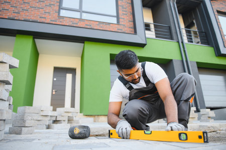 Indian worker lay paving tiles, construction of brick pavement, men's hands in glovesの写真素材