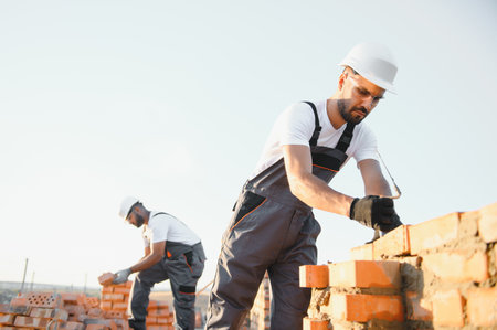 Professional construction workers build a brick house. Industrial theme of residential real estate construction.の写真素材