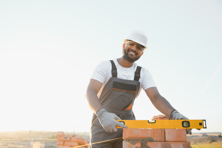 Construction worker man in work clothes and a construction helmet. Portrait of positive male builder in hardhat working at construction site.の写真素材