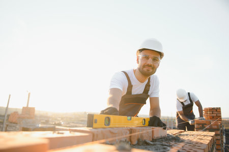 Construction worker man in work clothes and a construction helmet. Portrait of positive male builder in hardhat working at construction site.の写真素材