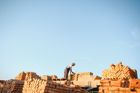 Installing brick wall. Construction worker in uniform and safety equipment have job on building.
