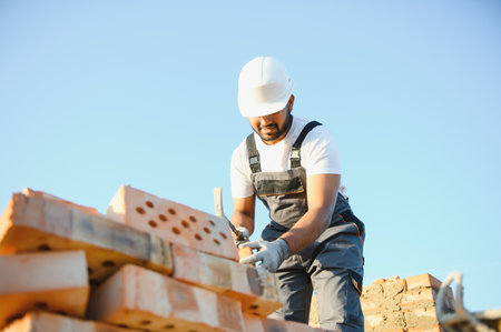 Construction worker man in work clothes and a construction helmet. Portrait of positive male builder in hardhat working at construction site.の写真素材