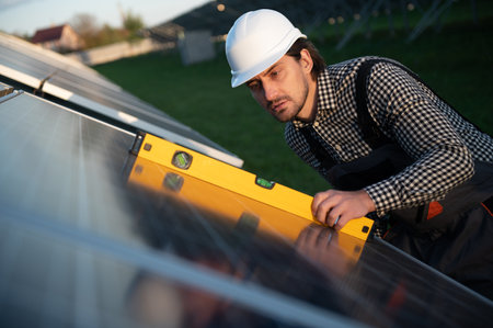 Man worker mounting photovoltaic solar panels. Engineer in helmet installing solar module system. Concept of alternative, renewable energy.の写真素材