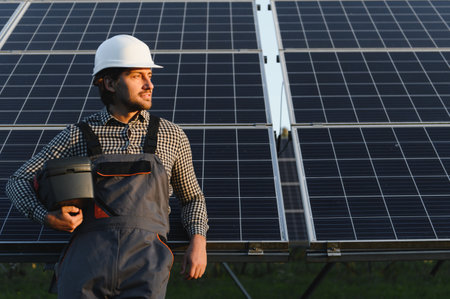 Man engineer in uniform working on solar panels power farm. Solar panel field. Clean energy...