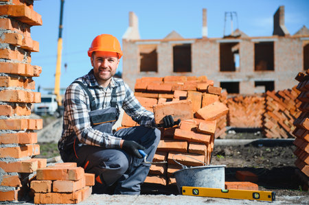 construction mason worker bricklayer installing red brick with trowel putty knife outdoors.