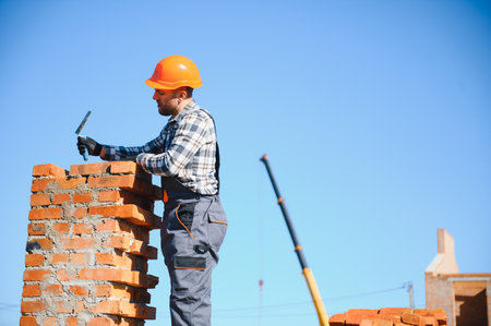 Installing brick wall. Construction worker in uniform and safety equipment have job on building.の写真素材