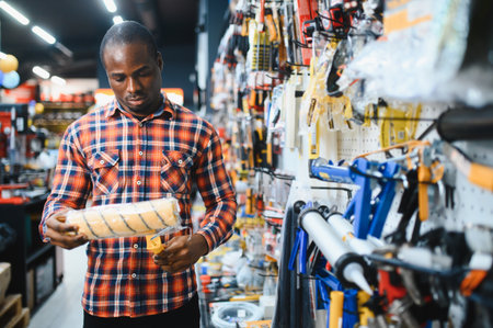 African american male customer in a modern hardware store chooses a paint roller.の写真素材