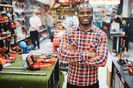 Confident smiling salesman on foreground in power tools store. Guy is ready to help clients on background.の写真素材