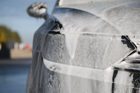 Modern car with white foam is washed at car wash. Car care. Detailing.の写真素材
