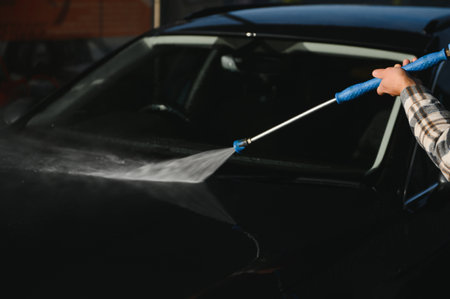 A man washes his car at a car wash. Self-service car wash.の写真素材