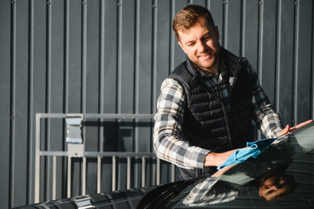 A man wipes his car with a microfiber towel after washing it at a car wash.の写真素材