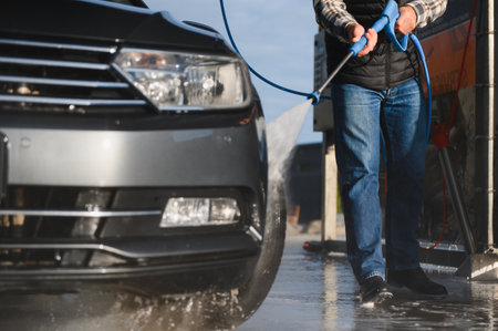 Car wash. Man washes car with water from high pressure washer.の写真素材