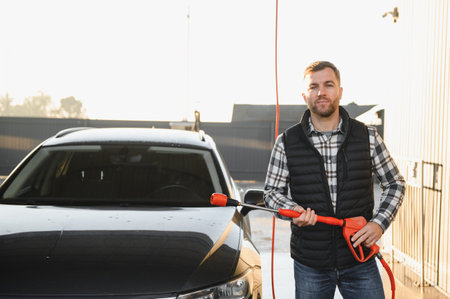 A man washes his car at a car wash. Self-service car wash.