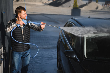 Car wash. Man washes car with water from high pressure washer.の写真素材