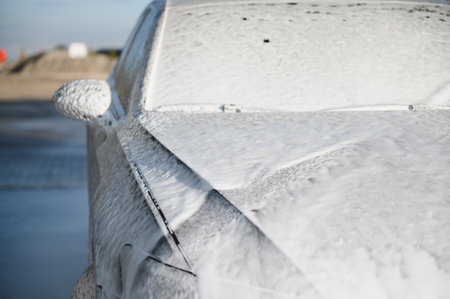Modern car with white foam is washed at car wash. Car care. Detailing.の写真素材