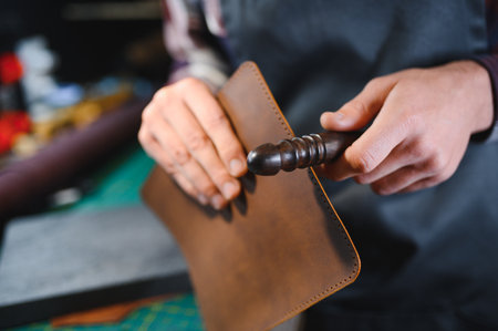 Man working with leather. Professional makes a wallet.