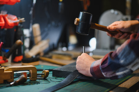 Working process of the leather belt in the leather workshop. Man holding crafting tool and working.