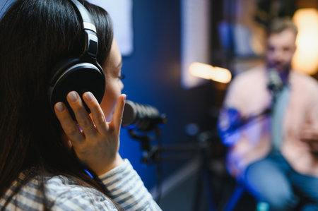 Side view of successful woman hosting interview podcasting man while recording with professional microphones, copy space.の写真素材