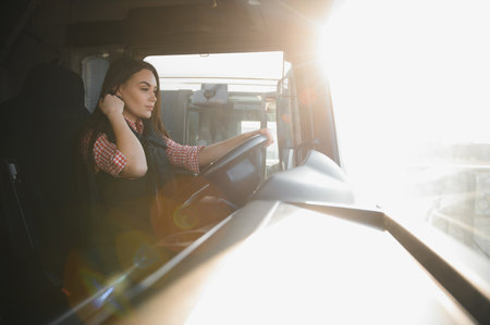 Portrait of young woman professional driver sitting and driving a big truck. Inside of vehicle....