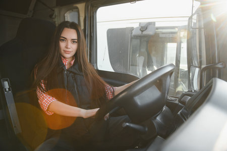 Portrait of a young woman professional truck driver sitting and driving big truck.の写真素材
