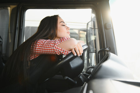 Woman lying on the steering wheel of the truck. Tired driver sleep at the wheel. The interior of the old lorry with a female driver resting. Pause while driving.の写真素材