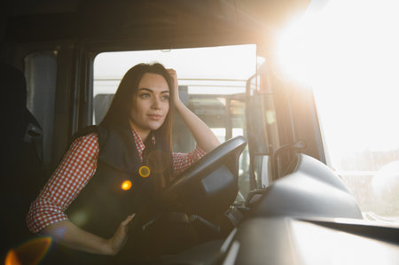 Portrait of a young woman professional truck driver sitting and driving big truck.の写真素材