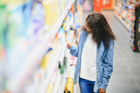 Interested young woman making purchases in household chemicals store, reading labels on bottles.の写真素材