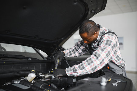 African man standing in a car repair shop.
