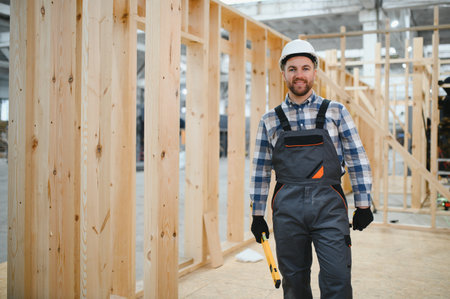 Portrait of a carpenter smiling with crossed arms in a lumber warehouse, showing expertise in the...