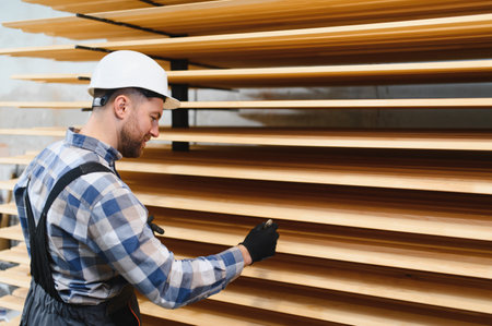 A worker varnishes boards for the construction of a wooden houseの写真素材