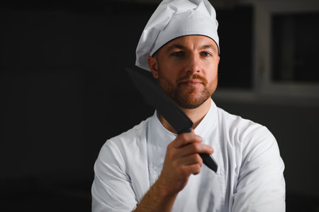 Portrait of a handsome young chef in the kitchen with his chef's knife.