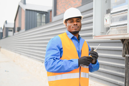 African American Electrical engineer approving power distribution box installation on site.
