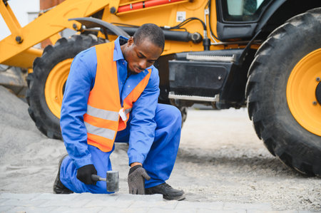 An African American worker lays pavers in a yard or sidewalk.