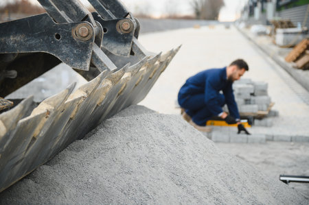 The master in gloves lays paving stones in layers. Laying gray concrete paving slabs in house...