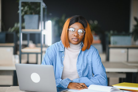 Focused serious African American female student studying in classroom, working on university assignment.の写真素材