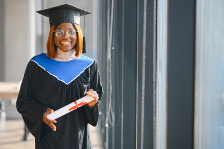 happy African American female student with diploma at graduation.の写真素材